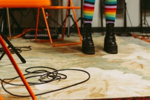 Feet of a student wearing black boots and rainbow-coloured socks on a beige rug.