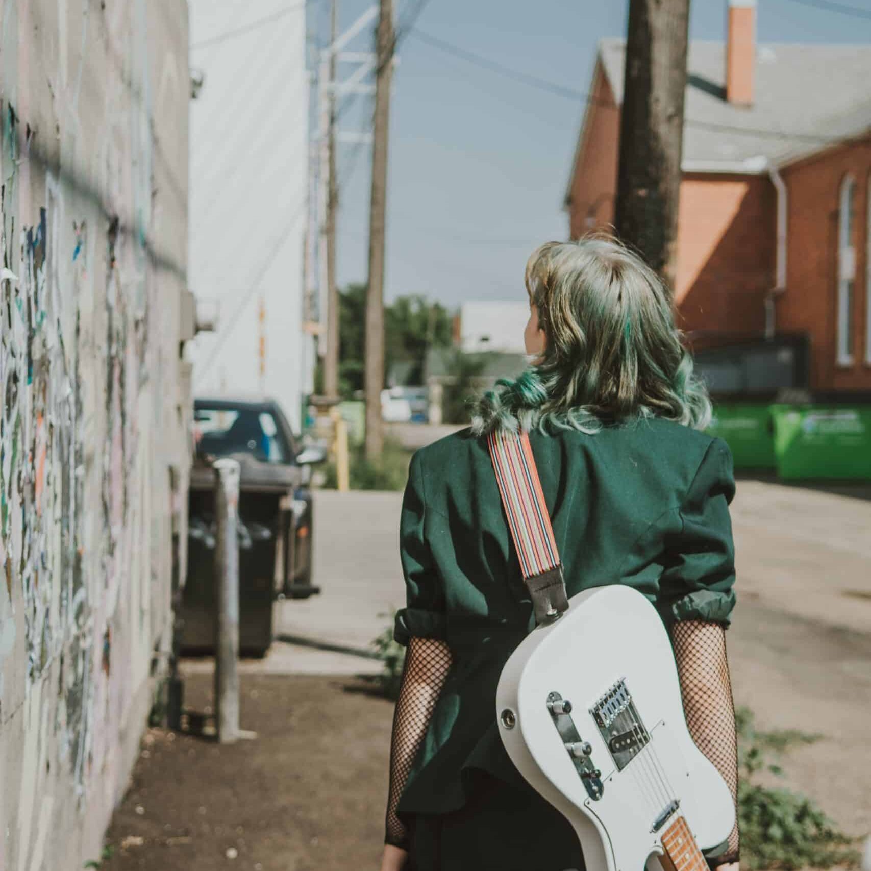 Ella Raven-Jackson walking with her guitar Ella Raven-Jackson walking with her guitar
